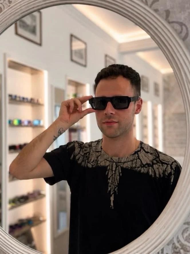 Prova di una montatura da sole nera davanti allo specchio in boutique